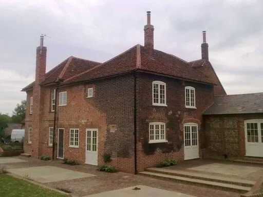 Red brick farmhouse with tall chimney stacks