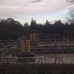 Chimney pots on rebuilt stacks seen above roof scaffolding at dusk