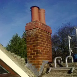 Restored red brick chimney stack with two terracotta pots
