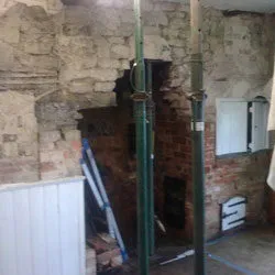Inglenook fireplace held up by steel props while the brickwork is rebuilt