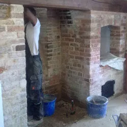 Inglenook fireplace with its brickwork being rebuilt