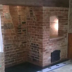 Rebuilt brick inglenook with a bread oven and cast iron door