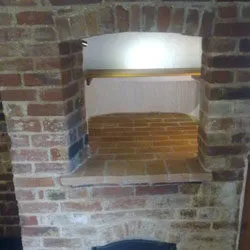 Restored brick bread oven recess within an inglenook